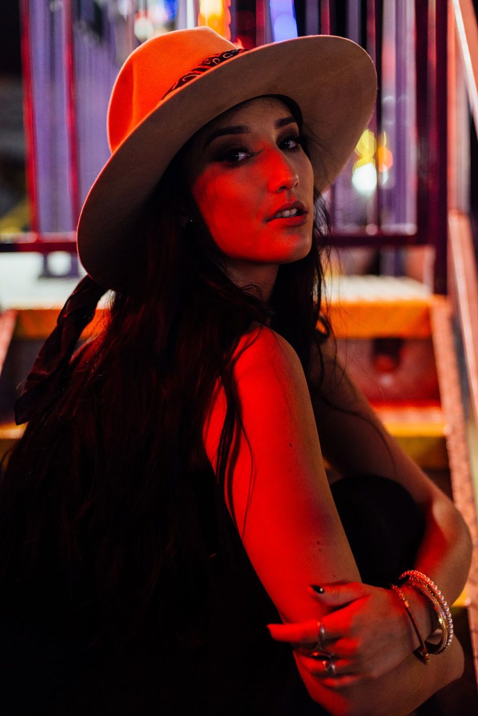 Stylish girl with long dark hair in trendy hat poses with arms crossed