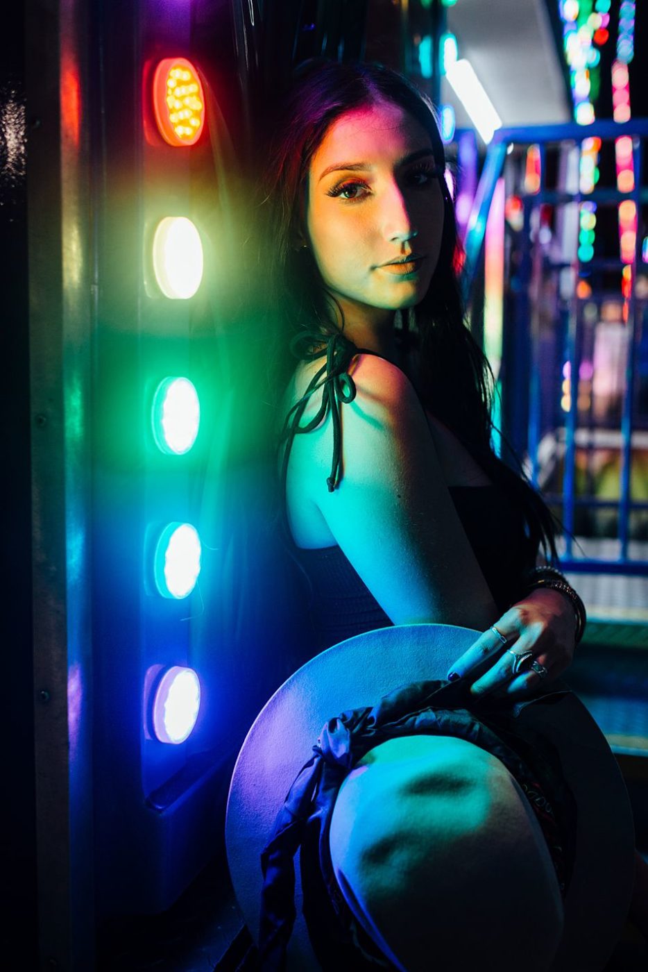Pretty young woman half-illuminated by the bright lights of a carnival ride with the other half of her face in the dark side
