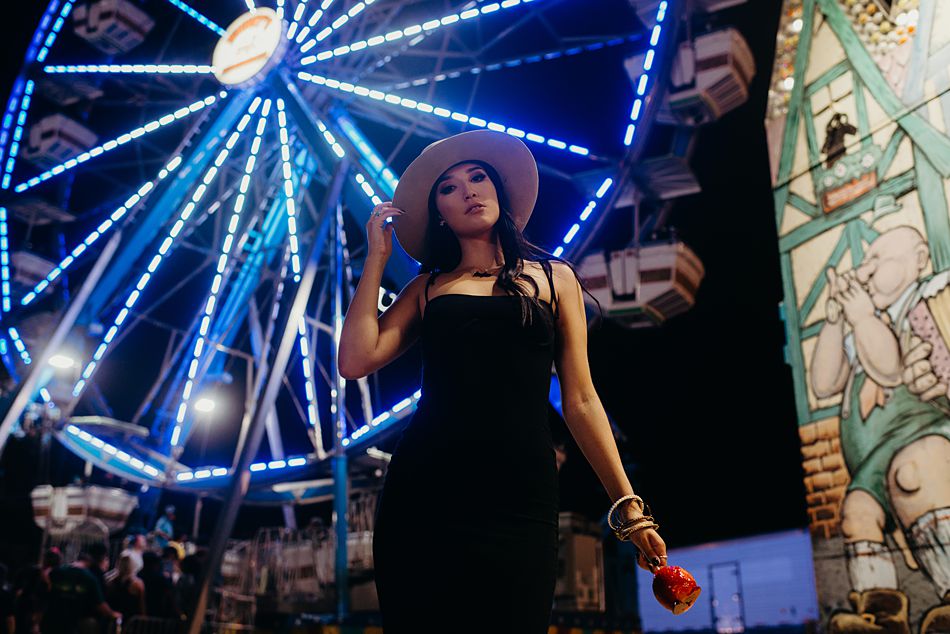 Pretty girl eating candy apple in front of a ferris wheel