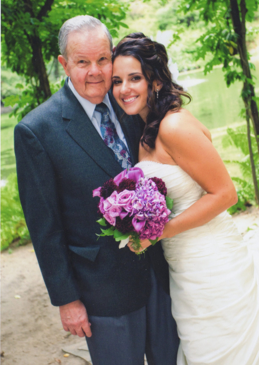grandfather and granddaughter pose together on her wedding day