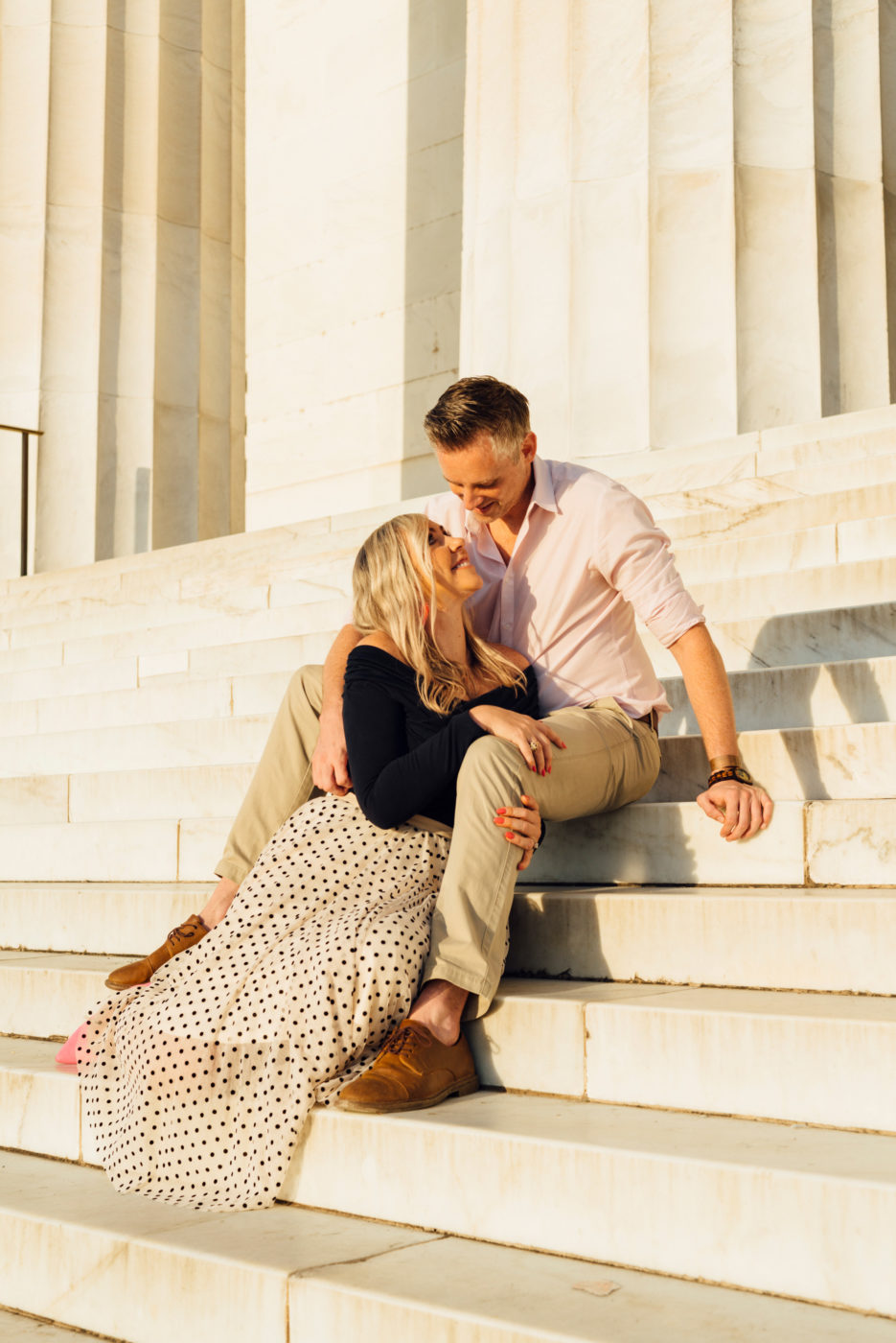 blonde couple sits on the steps of the Lincoln Memorial