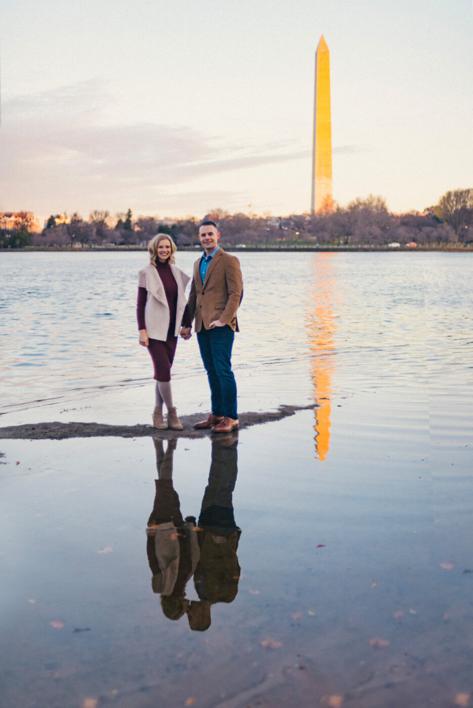 a couple stands in front of the Tidal Basin Reservoir on the National Mall in Washington D.C.